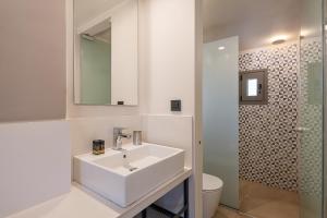 a white bathroom with a sink and a toilet at Elafonisi Resort by Kalomirakis Family in Elafonisi