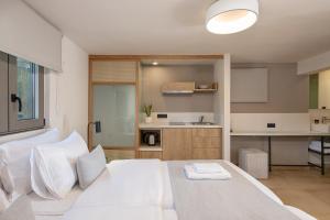 a bedroom with a white bed and a kitchen at Elafonisi Resort by Kalomirakis Family in Elafonisi