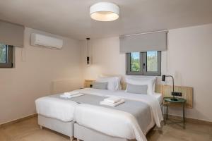 a bedroom with a large white bed with two towels on it at Elafonisi Resort by Kalomirakis Family in Elafonisi
