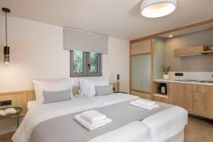 a bedroom with a large white bed with towels on it at Elafonisi Resort by Kalomirakis Family in Elafonisi
