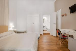 ein weißes Schlafzimmer mit einem Bett, einem Schreibtisch und einem Stuhl in der Unterkunft B&B Palermo Bella Rooms and Suites in Palermo