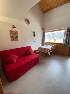 een woonkamer met een rode bank en een tafel bij Parenthèse à la montagne in Bessans