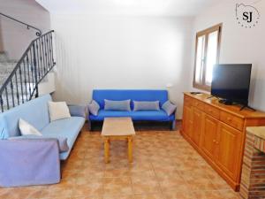 un soggiorno con un divano blu e una TV di Chalet con piscina (B) a Les tres Cales