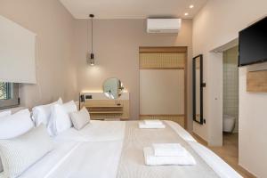 a bedroom with a large white bed and a mirror at Elafonisi Resort by Kalomirakis Family in Elafonisi