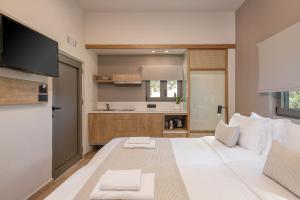 a bedroom with a large white bed and a kitchen at Elafonisi Resort by Kalomirakis Family in Elafonisi