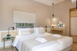 a bedroom with a large white bed with two towels on it at Elafonisi Resort by Kalomirakis Family in Elafonisi