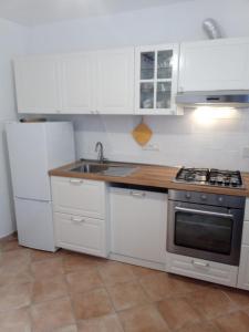 a kitchen with white cabinets and a sink and a refrigerator at da Barbara in Orco Feglino