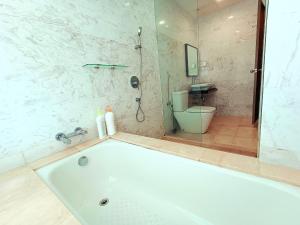 a white bath tub in a bathroom with a toilet at Silverscape Residence Melaka in Melaka