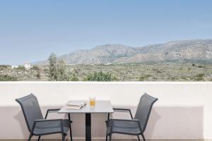 a table and chairs on a balcony with a view of mountains at Elafonisi Resort by Kalomirakis Family in Elafonisi