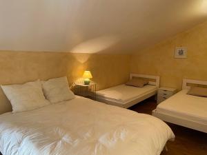 a bedroom with two beds and a table with a lamp at Le Clos des Figuiers - 3 Gîtes de caractère in Duravel
