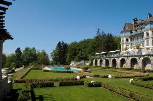 un grand bâtiment avec un jardin et une piscine dans l'établissement Château des Avenieres - Relais & Châteaux, à Cruseilles