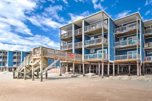 un gran edificio azul en la playa con escaleras de madera en North Topsail Beach Condo with Balcony!, en North Topsail Beach