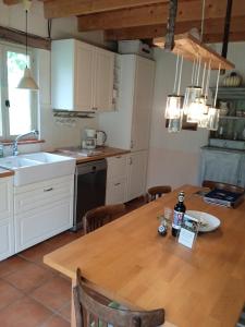 una cocina con mesa de madera y una cocina con armarios blancos. en Gite Le pigonnier Ecogite Le Luquet Saint Beauzeil 82150, en Saint-Beauzeil