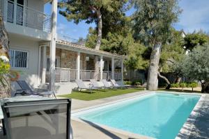 una piscina con sillas y una casa en Lagonisi luxurious residence Ruby's Pool Villa, en Lagonisi