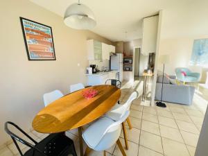 cocina y comedor con mesa de madera y sillas blancas en Bel appart tout confort en Annecy