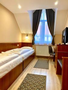 sypialnia z 2 łóżkami, biurkiem i telewizorem w obiekcie Borostyán Panzió w mieście Kaposvár