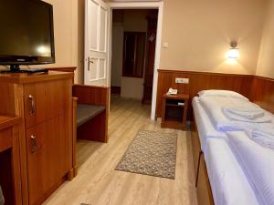 a bedroom with a bed and a flat screen tv at Borostyán Panzió in Kaposvár