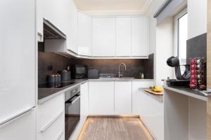 a white kitchen with white cabinets and a wooden floor at The Barclay Apartment in Perth