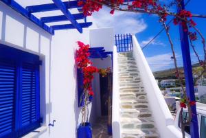 um edifício branco com portas azuis e escadas com flores vermelhas em Serene Hill em Naousa