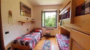 Cette chambre comprend 2 lits et une fenêtre. dans l'établissement Appartamento Isabella - Residence Montesole, à Ponte di Legno
