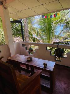 a table and chair in a room with a palm tree at Chandi Gaya Beach Guesthouse in Tangalle