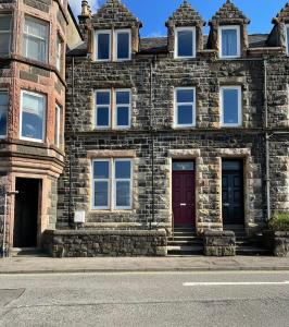 an old stone building with a red door at Killorn Guest House in Oban