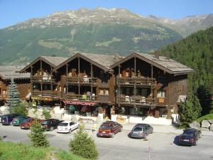 a large building with cars parked in a parking lot at Résidence Tarcianne in Grimentz
