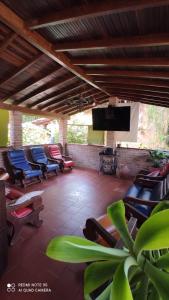 un porche cubierto con sillas, TV y una planta en CABAÑA EL PEZ SAN GIL en San Gil