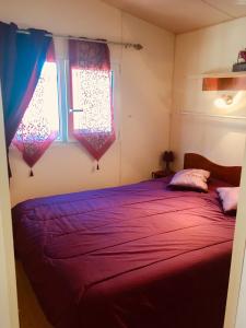 a bedroom with a red bed with two windows at Mobil Home Hyères les palmiers in Hyères