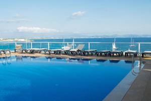 a swimming pool with tables and chairs next to the water at Hotel Club Sunway Punta Prima in Es Pujols