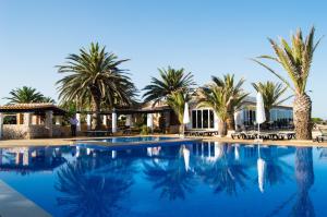 una piscina di fronte a un resort con palme di Hotel Club Sunway Punta Prima a Es Pujols