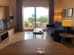 ein Wohnzimmer mit einer Couch, einem Fernseher und einem Tisch in der Unterkunft Fantástico Apartamento con vistas al mar zona Club la Costa Castillo Fuengirola in Fuengirola