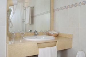 a white sink sitting under a mirror in a bathroom at Hotel Club Sunway Punta Prima in Es Pujols