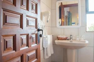 a bathroom with a door with a sink and a mirror at Hotel Club Sunway Punta Prima in Es Pujols