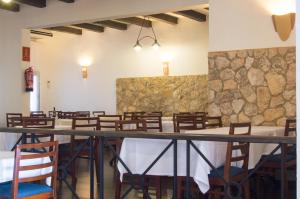 a dining room with tables and chairs and a stone wall at Hotel Club Sunway Punta Prima in Es Pujols