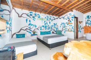 dwa łóżka w pokoju z malowidłem ściennym w obiekcie Ayenda Jardin de Provenza w mieście Medellín