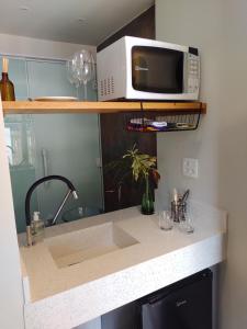 a microwave sitting on a shelf above a kitchen counter at Casa da Lu Itacoatiara -Suite Alto Mourão in Niterói +24 photos