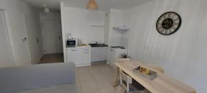 a kitchen with a table and a clock on the wall at Bel appt neuf - vue mer - terrasse - parking privé in Dunkerque
