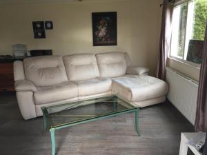 uma sala de estar com um sofá e uma mesa de café em vidro em Di'Mami House em Avenhorn