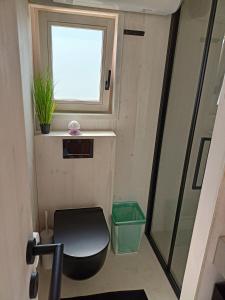 baño pequeño con aseo y ventana en BUQEZ RESORT, Vila 51 en Drage