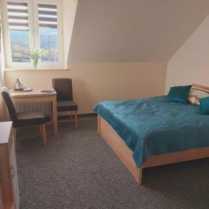 a bedroom with a bed and a desk and a table at Pokoje U lalusia in Muszyna