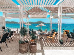 eine Terrasse mit Stühlen, Tischen und Meerblick in der Unterkunft BUQEZ RESORT, Vila 51 in Drage