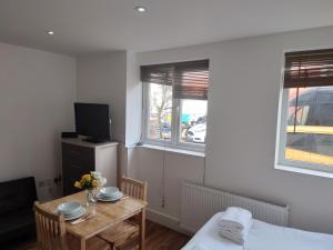 a small room with a table and a bed and two windows at City Sparrow 2C in London