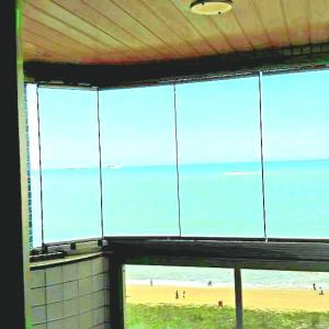 a window with a view of a beach and the ocean at LINDA VISTA PARA O MAR, APTO 2 QUARTOS, PRAIA DA COSTA, WI-FI, TV a CABO e LAZER in Vila Velha