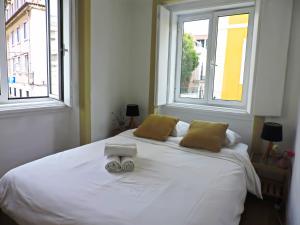 リスボンにあるNew Charming Flat - Lisbon Centerのベッドルーム1室(白いベッド1台、窓2つ付)