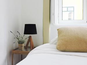 a bedroom with a bed with a lamp and a window at New Charming Flat - Lisbon Center in Lisbon
