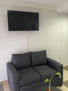 ein Wohnzimmer mit einem Sofa und einem TV an der Wand in der Unterkunft Depto Monte Grande a 15 minutos del Aeropuerto 1 con estacionamiento Desayuno gratuito y calefacción in Monte Grande
