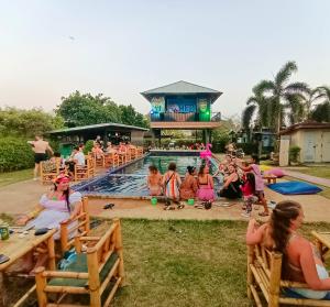 a group of people sitting around a swimming pool at WET! a Pool Party Hostel by Wild & Wandering in Haad Rin