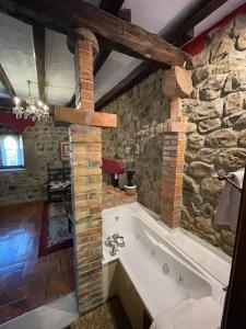 bañera en una habitación con pared de piedra en Hotel Casona de la Torre, en Ruente