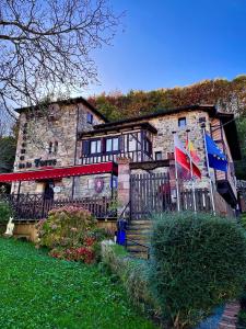 a stone house with two flags in front of it at Hotel Casona de la Torre in Ruente